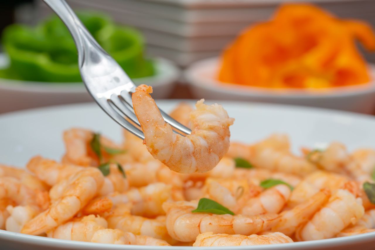 Garfo com camarão e prato com camarões